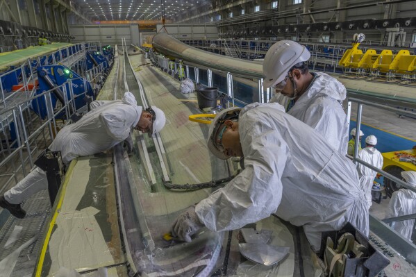 Employees work on a wind turbine blade at the Adani New Industries Limited in the port town of Mundra in Western India's Gujarat state, India, Wednesday, Sept. 20, 2023. It's one of the few locations in India where most solar energy components are made from scratch. (AP Photo/Rafiq Maqbool)