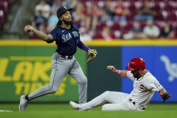 Seattle Mariners' J.P. Crawford, left, forces out Cincinnati Reds' Nick Martini at second base as he throws to first base to complete the double play during the eighth inning of a baseball game in Cincinnati, Wednesday, Sept. 6, 2023. (AP Photo/Aaron Doster)