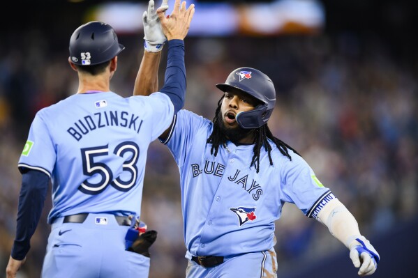 Toronto Blue Jays' Vladimir Guerrero Jr., right, celebrates with first base coach Mark Budzinski (53) after hitting a two-run single during sixth-inning baseball game action against the Minnesota Twins in Toronto, Saturday, May 11, 2024. (Chris Katsarov/The Canadian Press via AP)