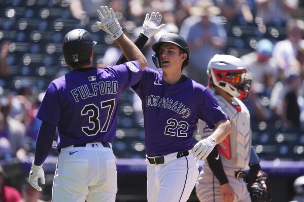 Colorado Rockies' Braxton Fulford, left, congratulates Mickey Moniak as he crosses home plate after hitting a three-run home run off Arizona Diamondbacks starting pitcher Brandon Pfaadt in the fifth inning of a baseball game Sunday, June 22, 2025, in Denver. (AP Photo/David Zalubowski)