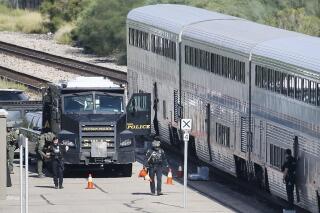 FILE - In this Oct. 4, 2021, file photo, a Tucson Police Department SWAT truck is parked near the last two cars of an Amtrak train in downtown Tucson, Ariz., following a shooting. The man who died in a gunfight in Tucson this month with law enforcement officers after fatally shooting a federal agent inside an Amtrak train was facing multiple California criminal charges. Two Arizona newspapers report that an Alameda County Sheriff's Office spokesman says 26-year-old Darrion Taylor was out of jail on bond. (Mamta Popat/Arizona Daily Star via AP, File)