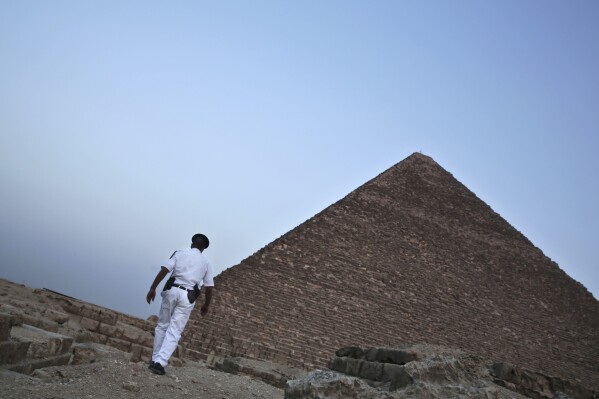 FILE - An Egyptian policeman walks near a pyramid in Giza, Egypt, on Nov. 9, 2015. A leading Egyptian opposition politician was targeted with spyware multiple times after announcing a presidential bid — including with malware that automatically infects smartphones, security researchers have found. They say Egyptian authorities were likely behind the attempted hacks. (AP Photo/Nariman El-Mofty, File)