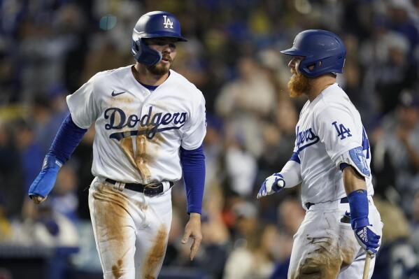 Los Angeles Dodgers' Gavin Lux, left, celebrates with Justin Turner after scoring off of a triple hit by Trea Turner during the third inning of a baseball game against the Cincinnati Reds in Los Angeles, Friday, April 15, 2022. (AP Photo/Ashley Landis)