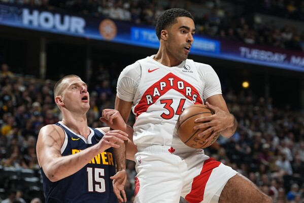 FILE - Toronto Raptors center Jontay Porter, right, pulls in a rebound as Denver Nuggets center Nikola Jokic, left, defends in the first half of an NBA basketball game Monday, March 11, 2024, in Denver. The NBA banned Toronto two-way player Jontay Porter on Wednesday, April 17, 2024, after a league probe found he disclosed confidential information to sports bettors and bet on games.(AP Photo/David Zalubowski, File)