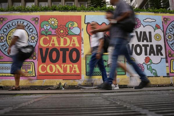 FILE - People walk past a mural that reads in Portuguese: “Every vote counts” in Sao Paulo, Brazil, Oct. 25, 2022. In a last-minute effort to win reelection on Sunday, Oct. 30, Marcos Rocha, the governor of Rondonia, in the Brazilian Amazon and a staunch ally of far-right President Jair Bolsonaro, revoked the protection of a large swath of the Amazon forest. (AP Photo/Matias Delacroix, File)