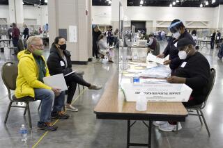 FILE - In this Nov. 20, 2020, file photo, election workers, right, verify ballots as recount observers, left, watch during a Milwaukee hand recount of presidential votes at the Wisconsin Center, in Milwaukee. The Republican-controlled Wisconsin Legislature was scheduled to vote Tuesday, May 11, 2021, on bills making it more difficult to vote absentee, proposals that are all-but certain to be vetoed by Democratic Gov. Tony Evers but that GOP lawmakers say are needed to address issues that arose in last year's presidential election. (AP Photo/Nam Y. Huh, File)