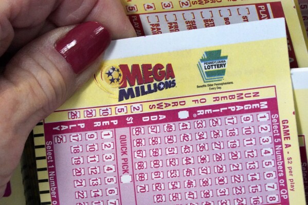 FILE - A Mega Millions wagering slip is held in Cranberry Township, Pa., Jan. 12, 2023. The huge $820 million Mega Millions jackpot up for grabs Tuesday, July 25, 2023, is the eighth-largest U.S. lottery prize.(AP Photo/Gene J. Puskar, File)