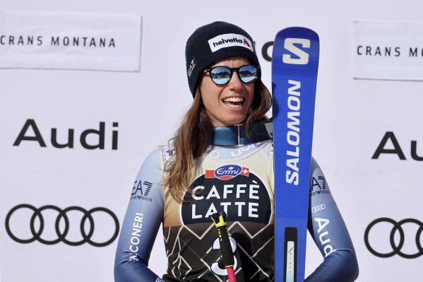 Italy's Marta Bassino celebrates on the podium after winning an alpine ski, women's World Cup downhill race, in Crans Montana, Switzerland, Saturday, Feb. 17, 2024. (AP Photo/Marco Trovati)