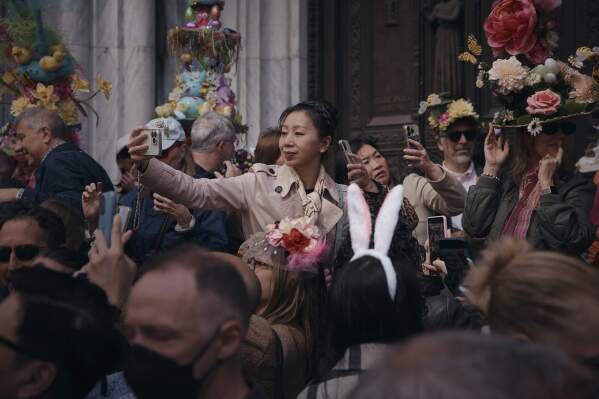 An attendee takes a selfie wearing decorated hats and costumes during the annual Easter Parade and Bonnet Festival in front of St. Patrick's Cathedral on Sunday, April 20, 2025, in New York. (AP Photo/Andres Kudacki)