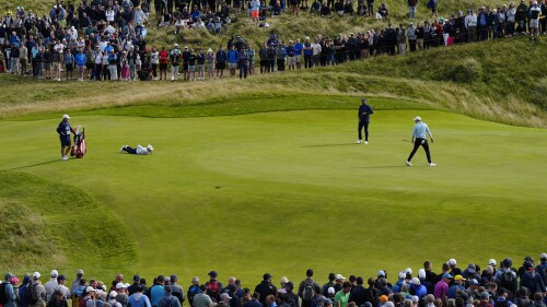 United States' Jordan Spieth, right looks back as England's Matt Fitzpatrick lies on the ground to look at the line of his putt on the 12th green during the second day of the British Open Golf Championships at the Royal Liverpool Golf Club in Hoylake, England, Friday, July 21, 2023. (AP Photo/Jon Super)