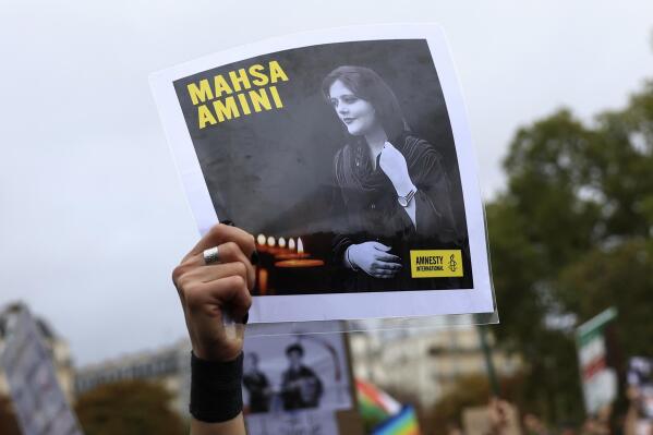 FILE - A protester shows a portrait of Mahsa Amini during a demonstration to support Iranian protesters standing up to their leadership over the death of a young woman in police custody, Sunday, Oct. 2, 2022 in Paris.  Anti-government demonstrations erupted Saturday, Oct. 8,  in several locations across Iran as the most sustained protests in years against a deeply entrenched theocracy entered their fourth week. The protests erupted Sept. 17, after the burial of 22-year-old Amini, a Kurdish woman who had died in the custody of Iran's feared morality police.   (AP Photo/Aurelien Morissard)