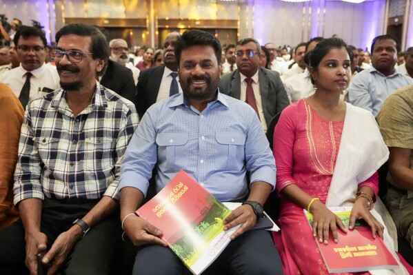 Anura Kumara Dissanayake, center, presidential candidate of opposition political party National People's Power holds a copy of his election manifesto in Colombo, Sri Lanka, Monday, Aug. 26, 2024. (AP Photo/Eranga Jayawardena)