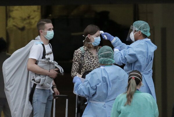 Health personnel wearing protection clothing check the temperature of a guest at the H10 Costa Adeje Palace hotel in La Caleta, in the Canary Island of Tenerife, Spain, Friday Feb. 28, 2020. Some guests have started to leave the locked down hotel after undergoing screening for the new virus that is infecting hundreds worldwide. (AP Photo/Joan Mateu)