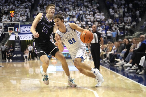 BYU guard Trevin Knell (21) drives around Evansville forward Ben Humrichous (13) during the second half of an NCAA college basketball game Tuesday, Dec. 5, 2023, in Provo, Utah. (AP Photo/Rick Bowmer)