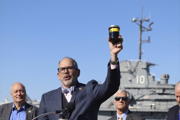 South Carolina Department of Natural Resources Director Robert Boyles holds a jar of toxic waste outside the USS Yorktown at a press conference in Mount Pleasant, S.C., on Tuesday, March 19, 2024. Officials are preparing to remove over 1.2 million gallons of hazardous liquids from the World War II-era aircraft carrier. (AP Photo/James Pollard)