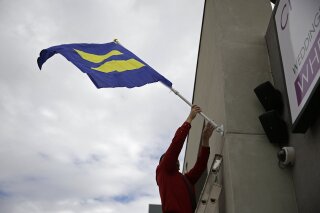 FILE - In this Tuesday, Oct. 7, 2014, file photo, Logan Seven raises an equality flag on the front of the Chapelle de l'amore wedding chapel, in Las Vegas. Proponents of a state ballot initiative that proposes removing a defunct ban on same-sex marriage from Nevada’s constitution are saying the uncertainty that’s followed the death of Justice Ruth Bader Ginsburg has injected a new sense of urgency, and anxiety, into their campaign. (AP Photo/John Locher, File)