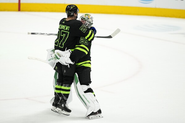 Dallas Stars' Mason Marchment (27) is lifted off the ice by goalie Jake Oettinger, right, as they celebrate the team's win in an NHL hockey game against the Edmonton Oilers, Wednesday, April 3, 2024, in Dallas. (AP Photo/Tony Gutierrez)