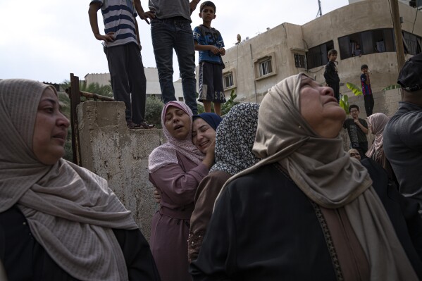 Relatives mourn people killed in an Israeli air strike in Gaza City on Monday, Oct. 9, 2023. Israel's military battled to drive Hamas fighters out of southern towns and seal its borders Monday as it pounded the Gaza Strip. (AP Photo/Fatima Shbair)