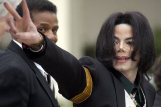 
              FILE - In this March 2, 2005 file photo, pop icon Michael Jackson waves to his supporters as he arrives for his child molestation trial at the Santa Barbara County Superior Court in Santa Maria, Calif. The estate of Michael Jackson on Thursday sued HBO over a documentary about two men who accuse the late pop superstar of molesting them when they were boys, saying the film violates a 1992 contract to air a Jackson concert. The lawsuit filed in Los Angeles County Superior Court alleges that by co-producing and airing "Leaving Neverland," the cable channel is committing breach of contract and breach of covenant, citing a section of the deal for “Michael Jackson in Concert in Bucharest: The Dangerous Tour” that states HBO would not disparage Jackson at the time or in the future. (AP Photo/Michael A. Mariant, File)
            