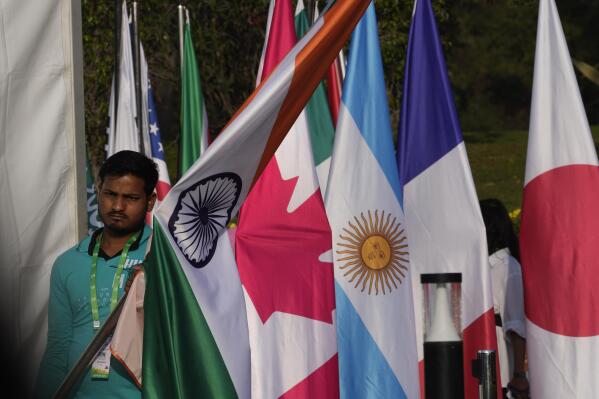 A worker carries Indian national flag to place it with those of other participating countries at the opening session of the G20 foreign ministers meeting, in New Delhi, India, Thursday, March 2, 2023. Top diplomats from the world’s major industrialized and developing nations on Thursday opened what are expected to be contentious talks dominated by Russia’s war in Ukraine and China’s moves to boost its global influence.(AP Photo/Manish Swarup)