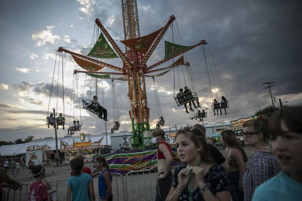 People wait to ride a revolving swing at the Perry State Fair in New Lexington, Ohio, Friday, July 24, 2020. In the towns that speckle the Appalachian foothills of southeast Ohio, the pandemic has barely been felt. Coronavirus deaths and racial protests - events that have defined 2020 nationwide - are mostly just images on TV from a distant America. (AP Photo/Wong Maye-E)