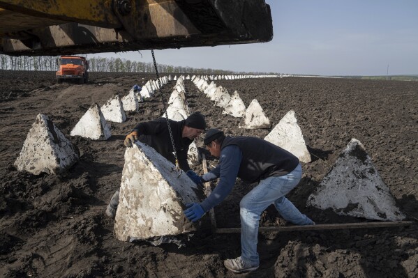 Workers install dragon teeth during the construction of new defensive positions close to the Russian border in Kharkiv region, Ukraine, on Wednesday, April 17, 2024. (AP Photo/Evgeniy Maloletka)
