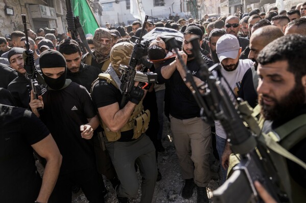 Palestinians carry the bodies of a militant killed in clashes during an Israeli military raid, Jenin refugee camp, West Bank, Friday, Nov. 10, 2023. (AP Photo/Majdi Mohammed)