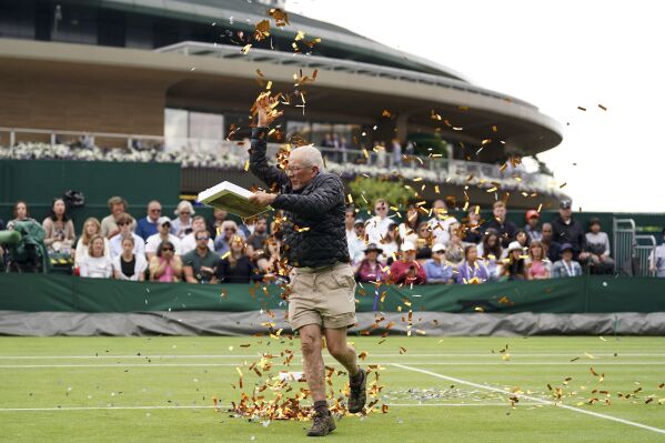 A Just Stop Oil protester on court 18 throwing confetti on to the grass during Britain's Katie Boulter's first-round singles match against Australia's Daria Saville on day three of the Wimbledon tennis championships in London, Wednesday, July 5, 2023. (Adam Davy/PA via AP)