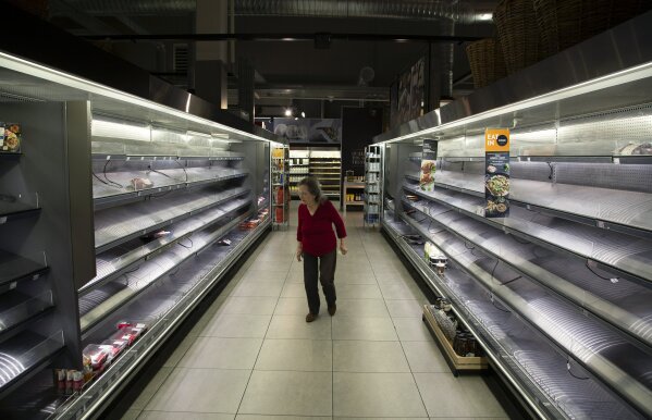 A woman looks at the few items left in the fresh meat and poultry fridges in a Johannesburg supermarket, Wednesday, March 18, 2020, amid panic-buying due to the coronavirus outbreak. For most people the virus causes only mild or moderate symptoms. For others it can cause more severe illness, especially in older adults and people with existing health problems. (AP Photo/Denis Farrell)