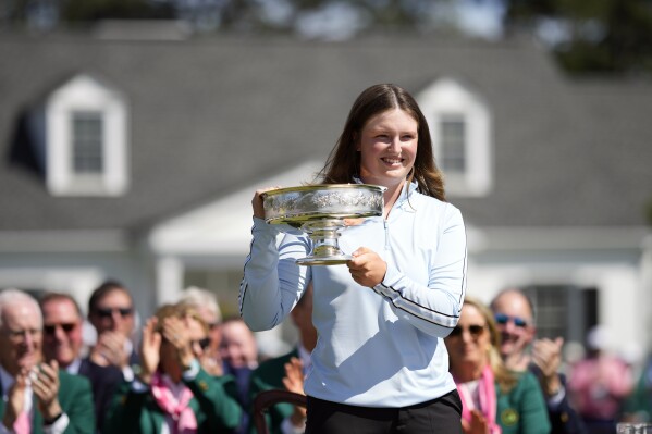 Lottie Woad, of England, poses with the trophy for photographers after winning the Augusta National Women's Amateur golf tournament, Saturday, April 6, 2024, in Augusta, Ga. (AP Photo/Matt Slocum)