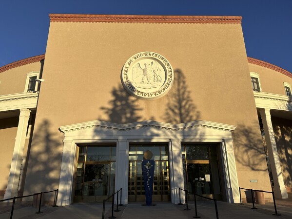 The sun sets on the New Mexico Statehouse in Santa Fe, N.M., Tuesday, Feb. 13, 2024, as legislators rush to pass bills before the end of a 30-day legislative session. Lawmakers are creating new endowments and trusts to support future spending amid a windfall in state income from oil production. (AP Photos/Morgan Lee)