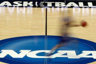 FILE - In this March 14, 2012, file photo, a player runs across the NCAA logo during practice in Pittsburgh before an NCAA tournament college basketball game. NCAA basketball administrators apologized to the women’s basketball players and coaches after inequities between the men’s and women’s tournament went viral on social media. Administrators vowed to do better. NCAA Senior Vice President of Basketball Dan Gavitt spoke on a zoom call Friday, March 19, 2021, a day after photos showed the difference between the weight rooms at the two tournaments. (AP Photo/Keith Srakocic, File)