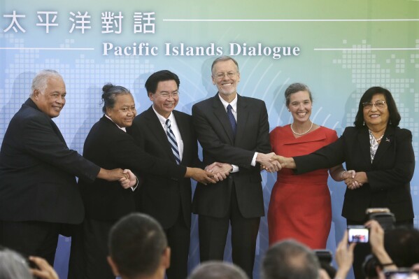 FILE - From left, Nauru Ambassador Jarden Kephas, Tuvalu Ambassador Limasene Teatu, Taiwan Foreign Minister Joseph Wu, American Institute in Taiwan (AIT) director William Brent Christensen, Sandra Oudkirk, U.S. Senior Official for APEC and Deputy Assistant Secretary for Australia, New Zealand, and the Pacific Islands in the State Department's Bureau of East Asian & Pacific Affairs, and Marshall Islands Ambassador Neijon Rema Edwards shake hands together at the inaugural Pacific Islands Dialogue in Taipei, Taiwan, on Oct. 7, 2019. The Pacific Island nation of Nauru says it is switching diplomatic recognition from Taiwan to China. The move on Monday, Jan. 15, 2024 leaves Taiwan with 12 diplomatic allies around the world. (AP Photo/Chiang Ying-ying, File)