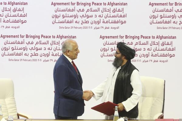 FILE - In this Feb. 29, 2020, file photo, U.S. peace envoy Zalmay Khalilzad, left, and Mullah Abdul Ghani Baradar, the Taliban group's top political leader shack hands after signing a peace agreement between Taliban and U.S. officials in Doha, Qatar. President Joe Biden and his national security team say the Trump administration tied their hands when it came to the U.S. withdrawal from Afghanistan. The argument that President Donald Trump's February 2020 deal with the Taliban set the stage for the weekend chaos that unfolded in Kabul has some merit. But, it's far from the full story. (AP Photo/Hussein Sayed, File)