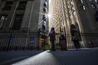 FILE - People pause near an entrance to the New York Stock Exchange in New York, March 19, 2024. (AP Photo/Eduardo Munoz Alvarez, File)
