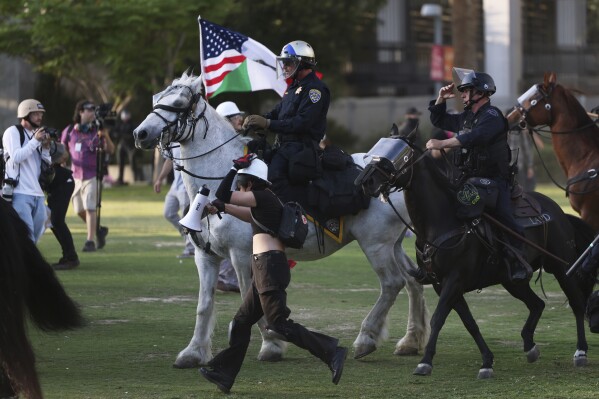 Los Angeles Metro police on horseback disperse protesters on Wednesday, June 11, 2025, in Los Angeles. (AP Photo/Ethan Swope)