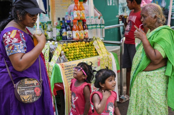 Women sip cool drinks as little girls wait for their turn at a roadside stall in Kolkata, India, Friday, May 3, 2024. (Ǻ Photo/Bikas Das)