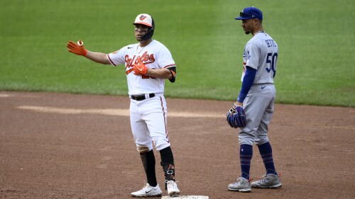 Baltimore Orioles' Ramon Urias, left, gestures as he stands on second after hitting a double during the third inning of a baseball game next to Los Angeles Dodgers second baseman Mookie Betts (50), Wednesday, July 19, 2023, in Baltimore. (AP Photo/Nick Wass)