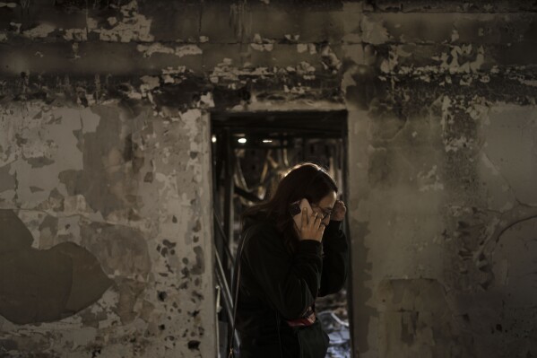 Sharon Alony Cunio calls a relative on Monday, Jan. 15, 2024, during a visits to the ruins of her home in Kibbutz Nir Oz, from where she was kidnapped with her family and taken to the Gaza Strip on Oct. 7, 2023, by Hamas militants. She and her two daughters were freed in November, but her husband remains in captivity. (AP Photo/Maya Alleruzzo)