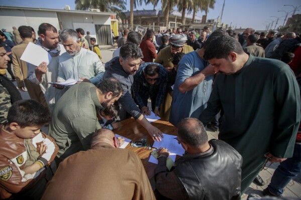 FILE - Supporters of the Shiite cleric Muqtada al-Sadr sign a pledge to stand against homosexuality or LGBTQ, outside a mosque in Kufa, Iraq, Friday, Dec. 2, 2022. Human rights groups and diplomats criticized a law that was quietly passed by the Iraqi parliament over the weekend that would impose heavy prison sentences on gay and transgender people. (AP Photo/Anmar Khalil, File)