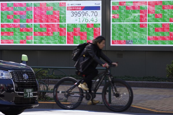 A cyclist moves past an electronic stock board showing Japan's Nikkei 225 index at a securities firm Wednesday, April 10, 2024 in Tokyo. (AP Photo/Shuji Kajiyama)