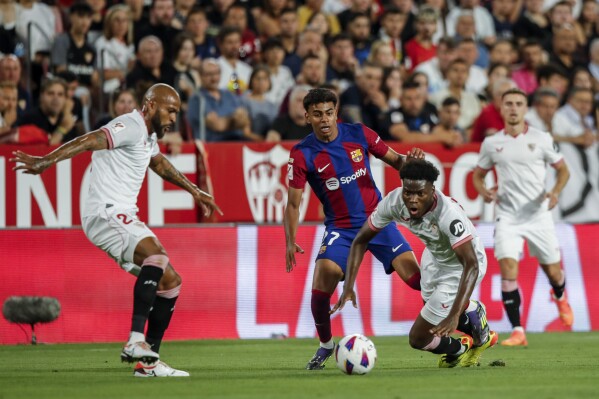 Barcelona's Lamine Yamal, center, vies for the ball with Sevilla's Lucien Agoume during a Spanish La Liga soccer match between Sevilla and FC Barcelona at the Ramon Sanchez Pizjuan stadium in Seville, Spain, Sunday, May 26, 2024. (AP Photo/Fermin Rodriguez)