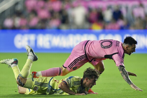 Inter Miami forward Lionel Messi falls on New York Red Bulls midfielder Daniel Edelman during the first half of an MLS soccer game, Saturday, May 4, 2024, in Fort Lauderdale, Fla. (AP Photo/Michael Laughlin)