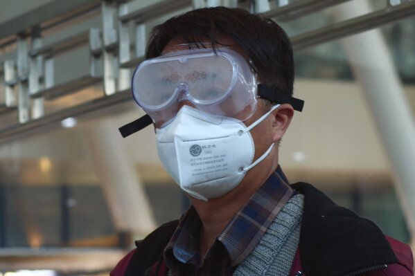 A traveler stares out of a fogged mask while waiting for a train to Beijing in Wuhan, China, Wednesday, April 15, 2020. Wuhan, the city at the center of the global coronavirus epidemic, lifted a 76-day lockdown and allowed people to leave for destinations across China. (AP Photo/Sam McNeil)