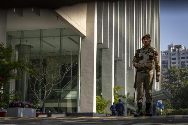 An armed security person stands stand guard at the gate of a building housing BBC office in New Delhi, India, Wednesday, Feb. 15, 2023. India’s tax officials searched BBC offices in India for a second straight day on Wednesday questioning the staff about the organization's business operations in the country, staff members said. (AP Photo/Altaf Qadri)