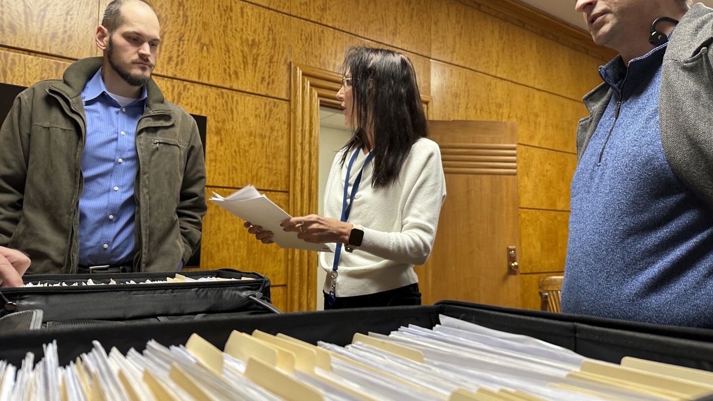 FILE - North Dakota State Elections Specialist Lee Ann Oliver, center, talks with Retire Congress North Dakota Chairman Jared Hendrix, at left, and U.