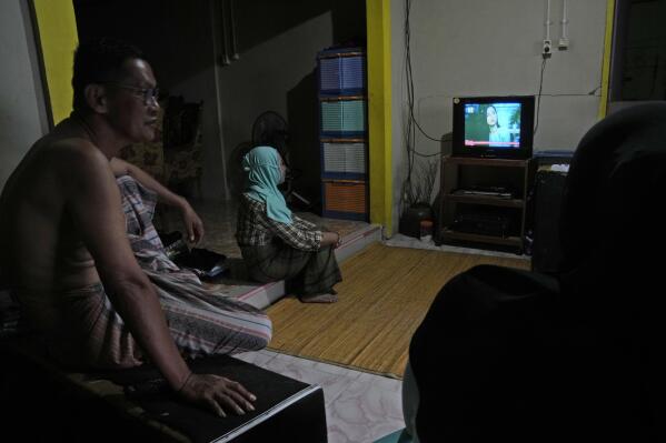 A family watches television with electricity supplied by a solar power plant in Karampuang Island, West Sulawesi, Indonesia, Thursday, Dec. 22, 2022. While Indonesia has vast renewable and green energy potential from solar, wind, geothermal and other sources, experts warn that the vast archipelago nation faces unique financial, policy, infrastructure and other challenges that will require innovation. (AP Photo/Dita Alangkara)