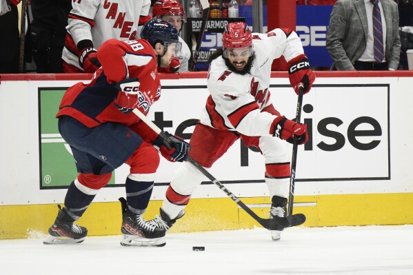 Carolina Hurricanes defenseman Jalen Chatfield (5) and Washington Capitals left wing Andrew Mangiapane (88) battle for the puck in the first period of Game 1 of a second-round NHL hockey playoff series Tuesday, May 6, 2025, in Washington. (AP Photo/Nick Wass)