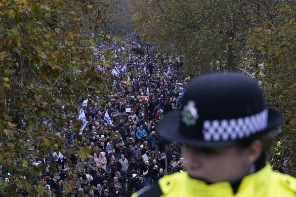 A policewoman stand guard on a bridge as an anti-Semitism demonstration with protesters holding placards flags and banners, including the flag of Israel, takes place in London, Sunday, Nov. 26, 2023. (AP Photo/Alberto Pezzali)