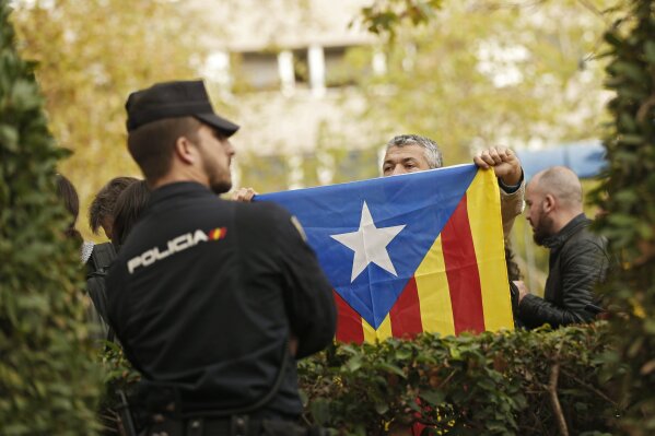 
              A man holds up an "esteladas", or Catalonia independence flag, in front of a Spanish national police officer outside the National Court in Madrid, Thursday, Nov. 2, 2017. A Spanish judge has ordered nine ex-members of the government in Catalonia jailed while they are investigated on possible charges of sedition, rebellion and embezzlement. (AP Photo/Francisco Seco)
            